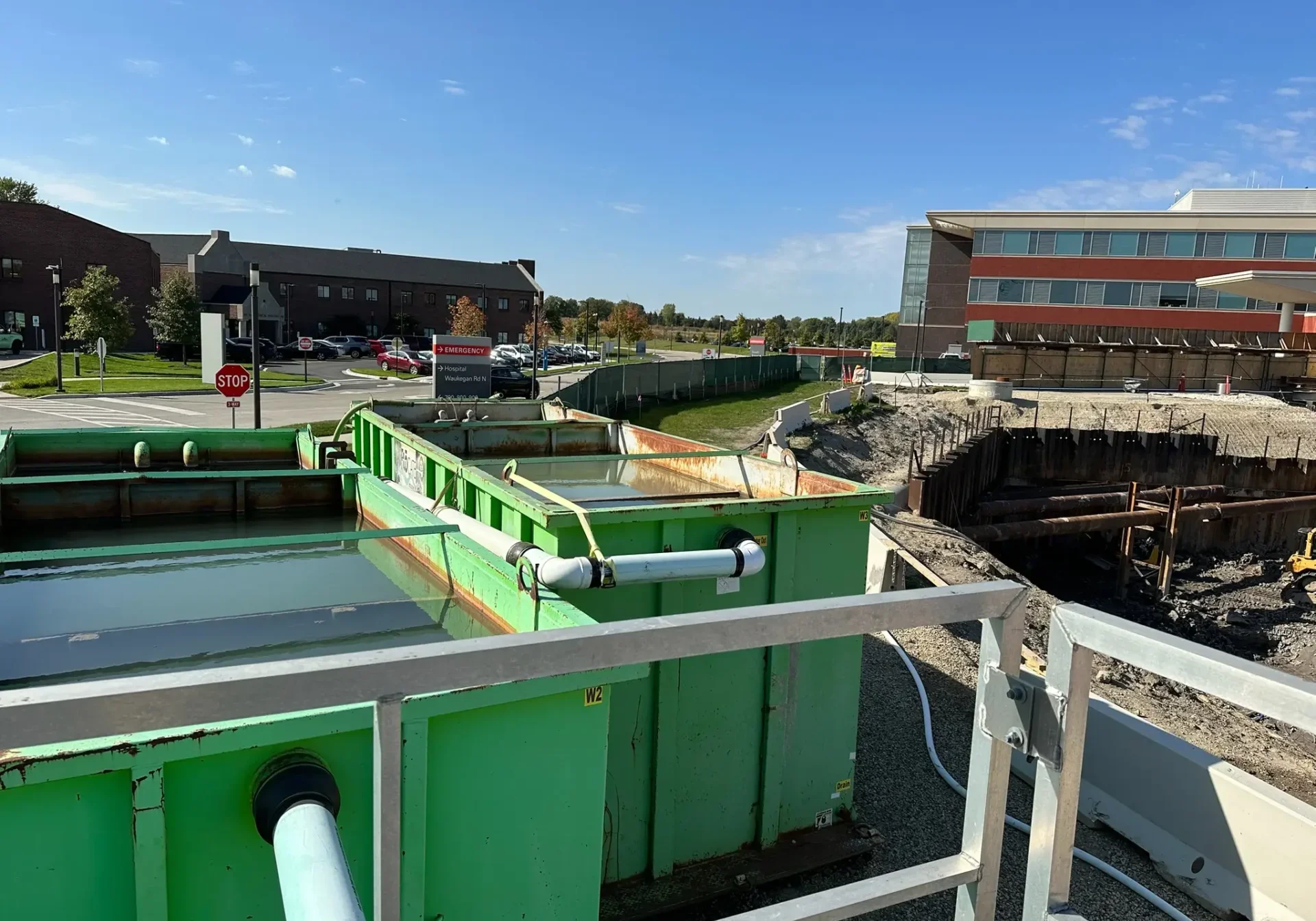 A green boat docked near industrial buildings under a clear sky.